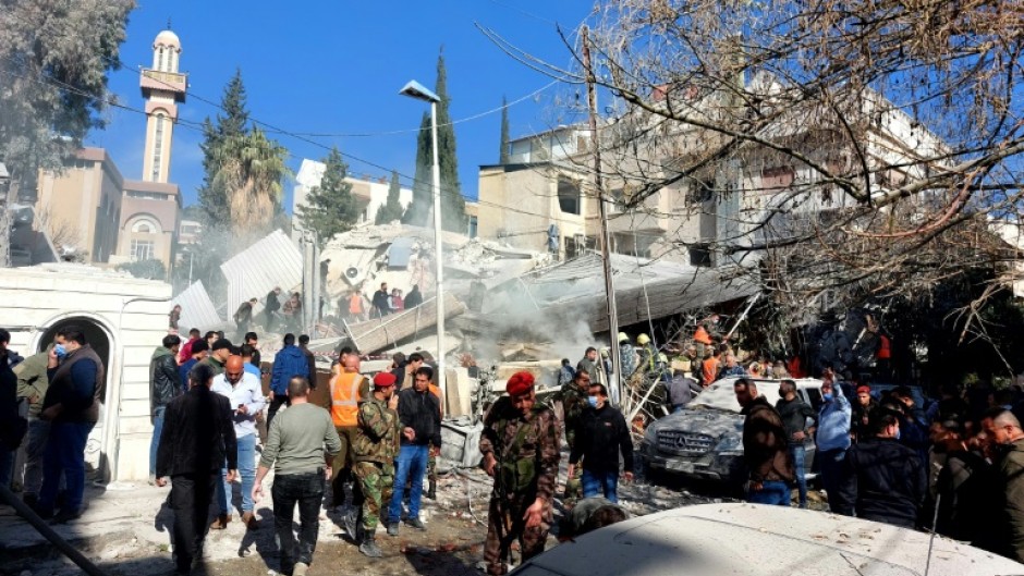 People and security forces gather in front of a building destroyed in a reported Israeli strike in Damascus on January 20