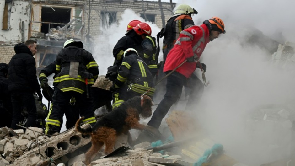 Members of a search and recovery team work with a search dog at the site of a missile attack in Kharkiv