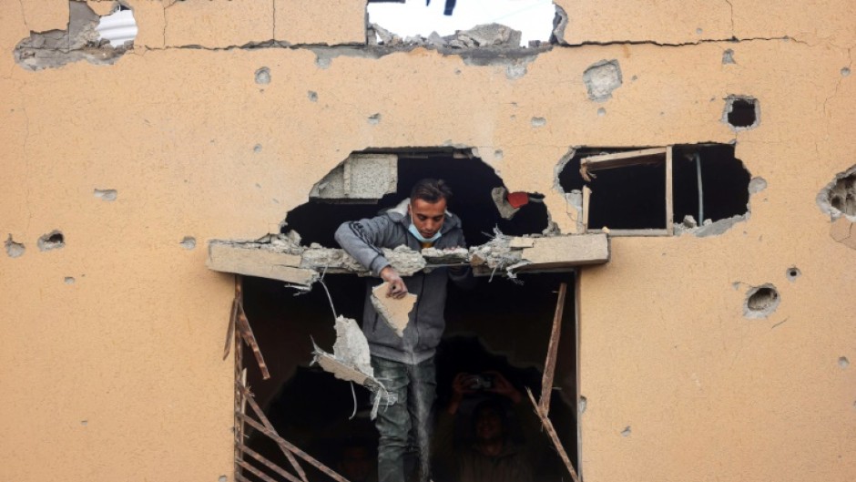 A man looks through the window of a building damaged by Israeli bombing in Rafah as battles between Israel and the militant group Hamas continue