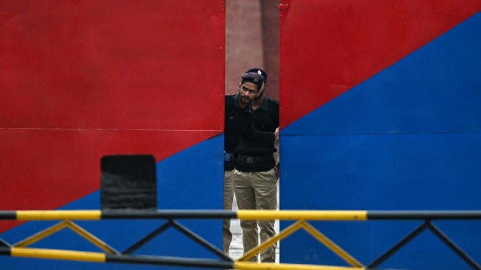 A policeman peeps through the main gate of the Adiala jail during the hearing of jailed former prime minister Imran Khan