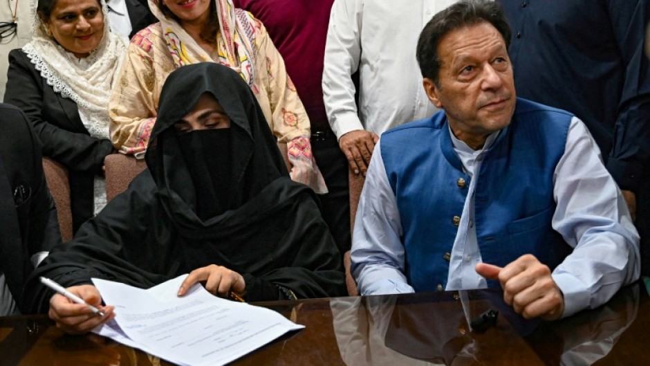 Imran Khan and his veiled wife Bushra Bibi signing court documents in Lahore last year. A judge ruled on Saturday that their marriage was illegal