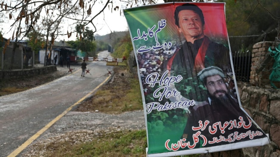 A poster with a picture of Pakistan's former prime minister Imran Khan (top) reading "Revenge of oppression with vote" hangs on a tree outside his residence guarded police in the Banigala area of Islamabad on February 1, 2024