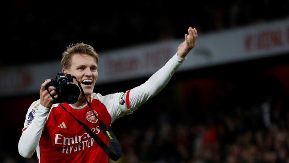 Martin Odegaard picks up a camera and takes pictures after Arsenal's win over Liverpool