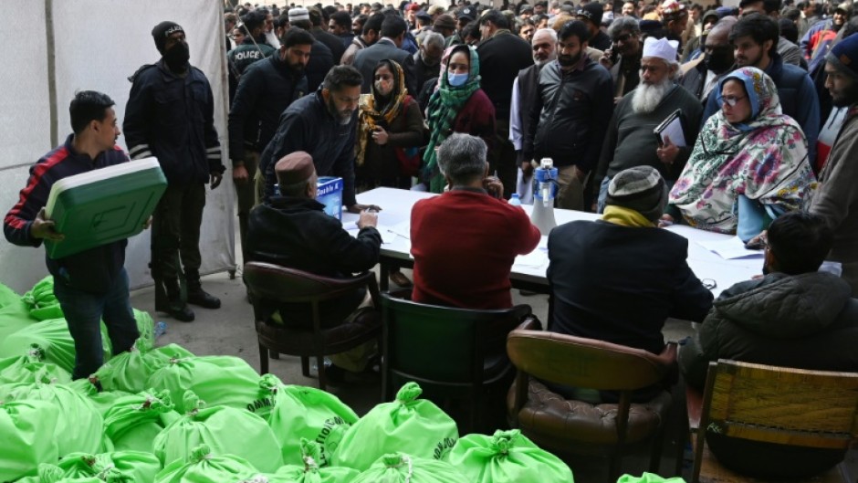 Returning officers wait to collect sacks of voting materials to polling stations from a distribution centre in Lahore, eastern Pakistan