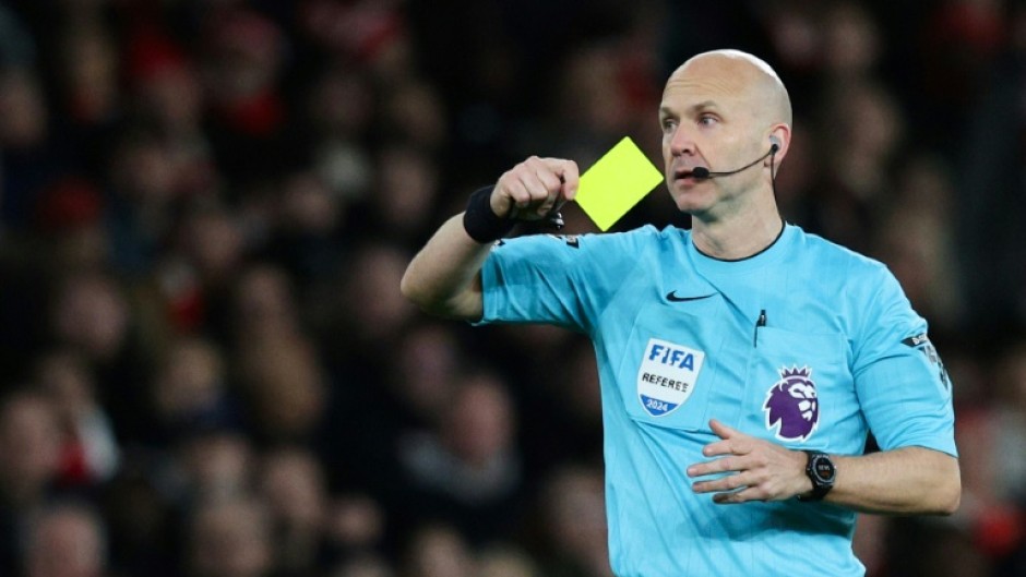 Premier League referee Anthony Taylor shows a yellow card