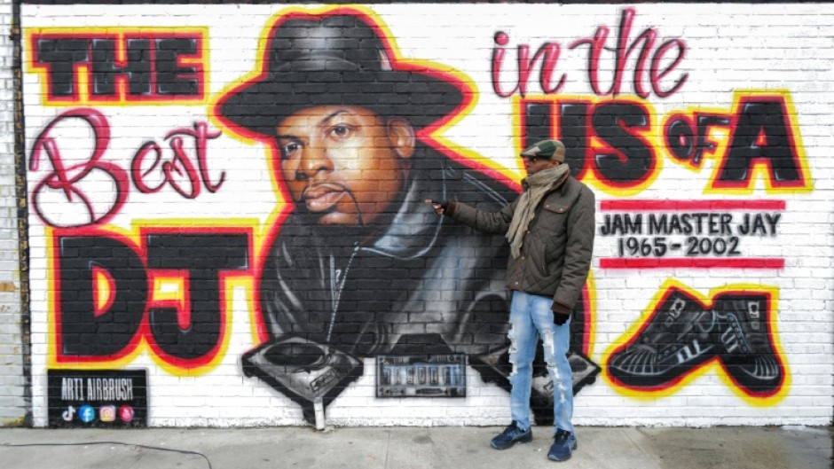 Local resident Jacob Rosthein poses before a mural paying tribute to late Run-DMC's Jam Master Jay in the Hollis neighborhood of Queens, as the trial into artist's murder gets underway