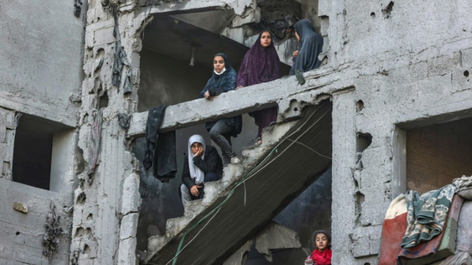 Palestinian women and children look at the damage from overnight Israeli air strikes in the Rafah refugee camp in the southern Gaza Strip