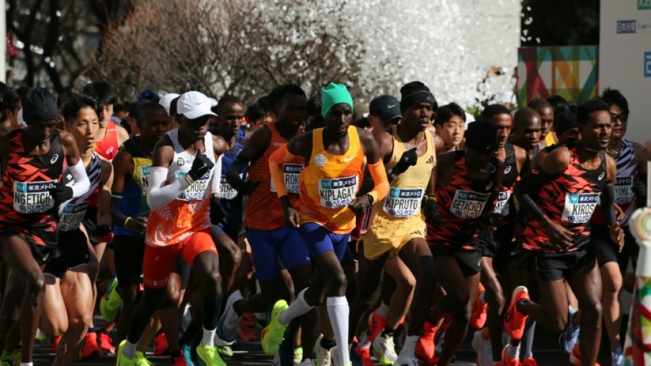 Men's elite runners including eventual winner Benson Kipruto (4th from right) and Eliud Kipchoge (white cap) set off at the start of the Tokyo marathon  