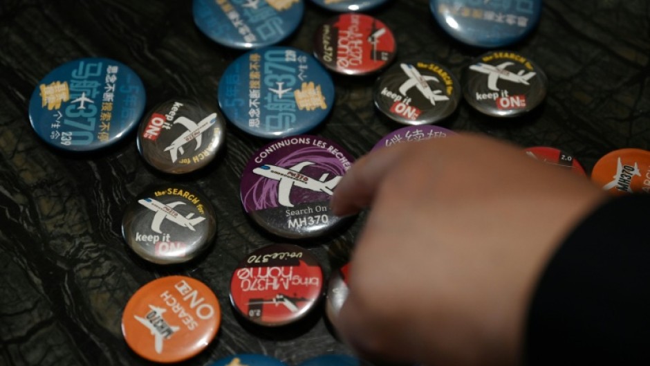 Jiang Hui, whose mother was on board flight MH370, shows buttons commemorating the missing flight