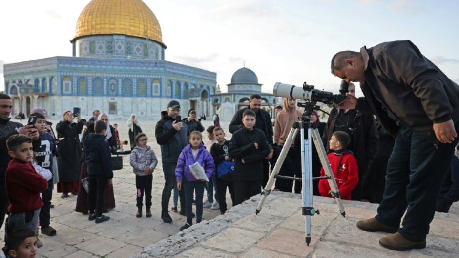 A man uses a telescope to look for the moon to mark the start of the Muslim holy month of Ramadan near the Dome of the Rock in Jerusalem