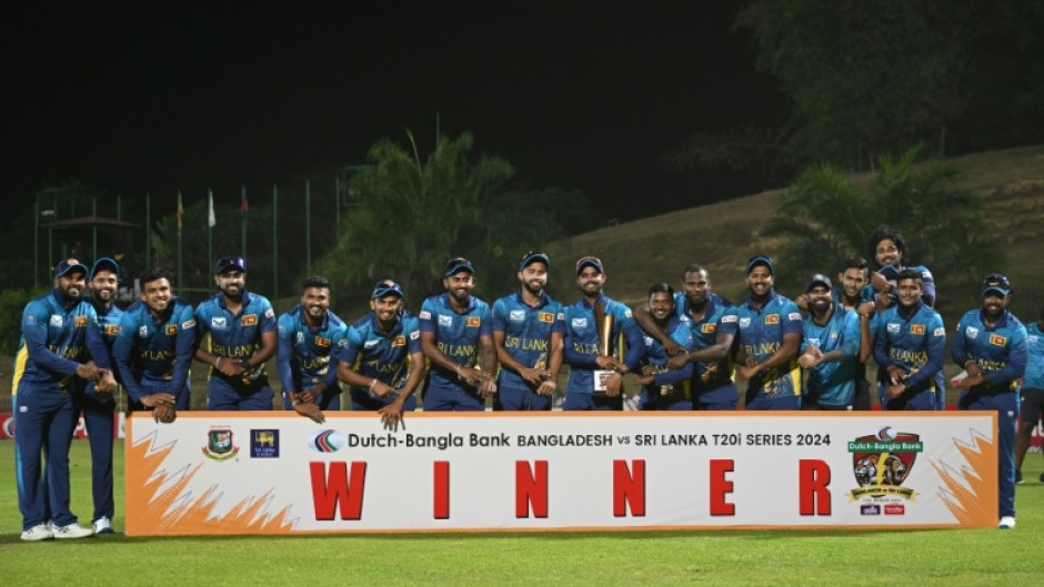 Sri Lanka's cricketers pose with the Twenty20 trophy after winning the three-match series against Bangladesh 2-1 -- pointing to their watches in an apparent reference to  the "timed out" controversy of last year's World Cup 