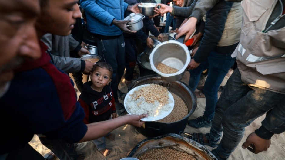 Displaced Palestinians collect food donated by a charity before an iftar meal, the breaking of fast, on the first day of the Muslim holy fasting month of Ramadan, in Rafah in the southern Gaza Strip on March 11, 2024