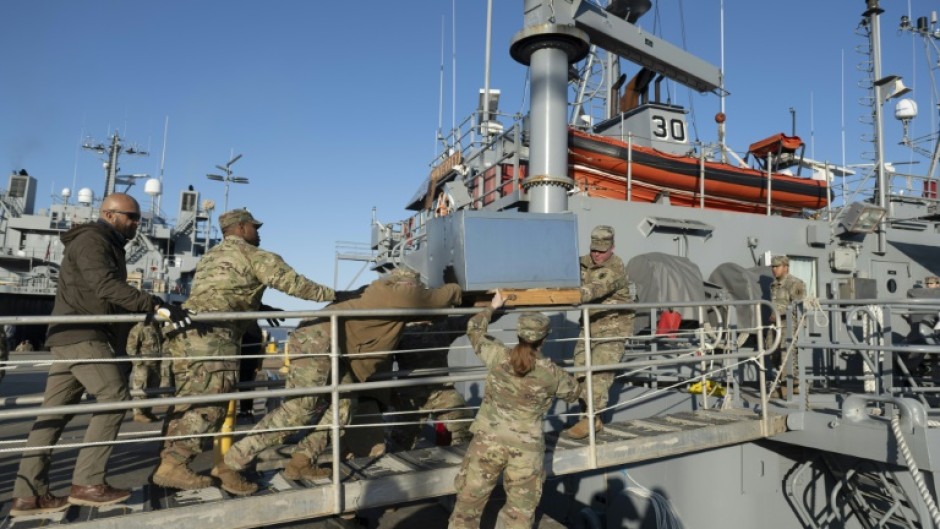 US Army soldiers load an AC unit aboard the USAV Monterey on March 12, 2024 ahead of the vessel's departure for an operation to construct a temporary port on Gaza's coast