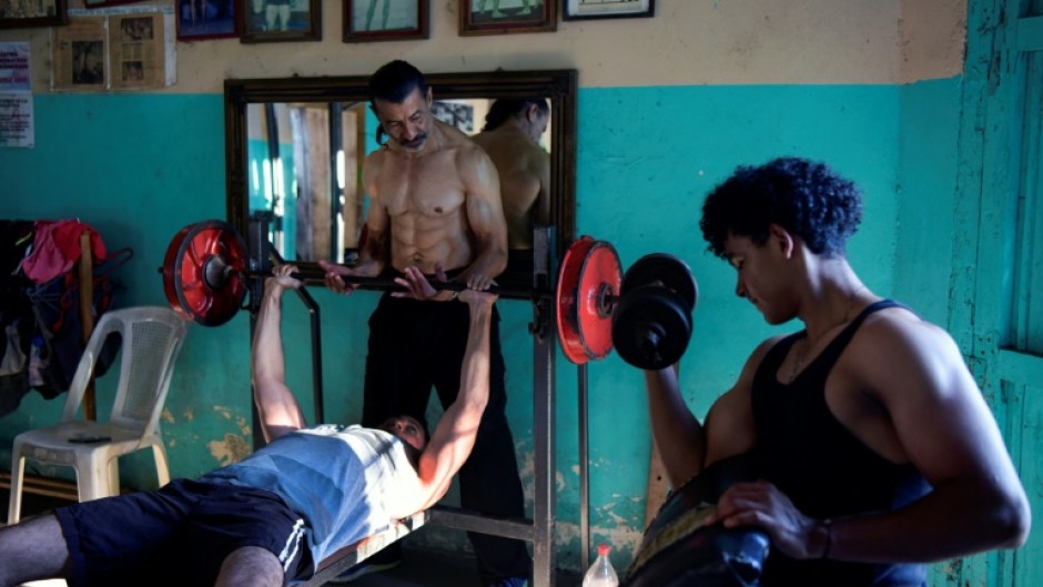 Walter Perez (C) helps a young man train in the gym he and his brother Arturo run in a town south of Managua