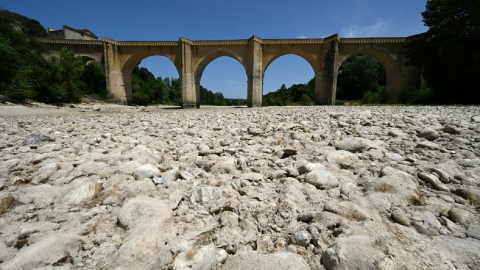 (FILES) A photograph shows the parched river bed of the Gardon near the Saint-Nicolas de Campagnac bridge in Saint-Anastasie, southern France, after a heat wave hit in June 2022