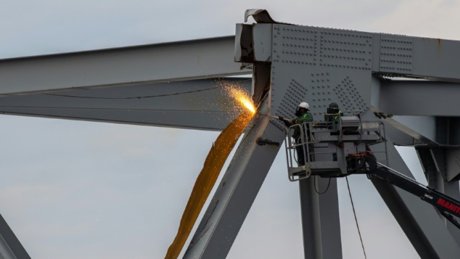 A handout photo from the US Coast Guard shows demolition crews cutting the top portion of the north side of the collapsed Francis Scott Key Bridge on March 30, 2024