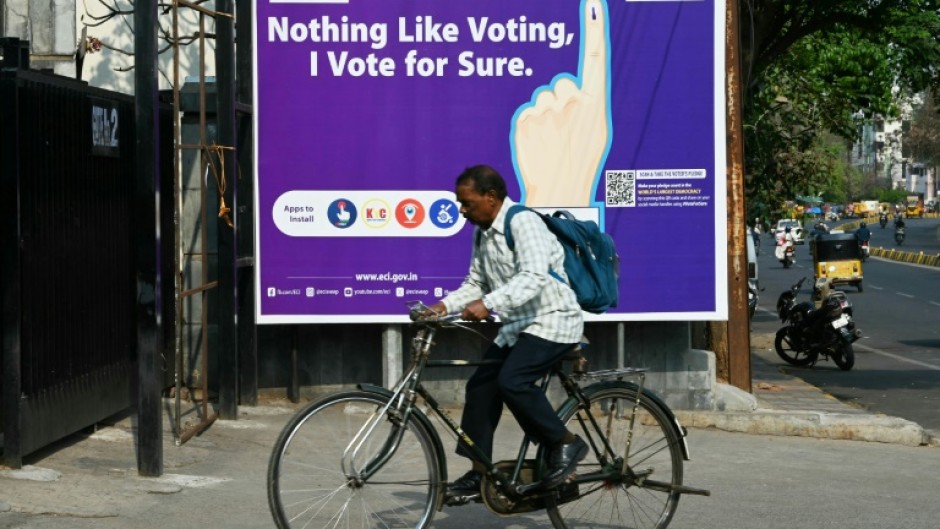 A man rides past an election awareness poster displayed on a street ahead of India’s upcoming general elections, in Hyderabad 