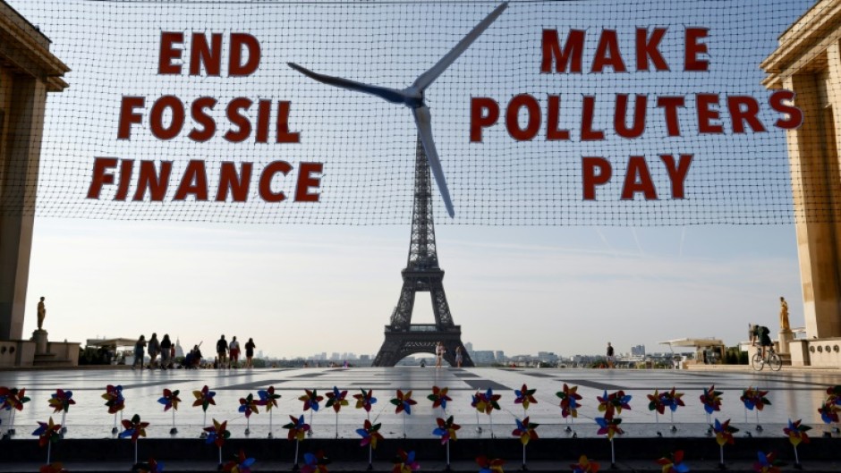 Activists demonstrate in Paris against fossil finance, with the Eiffel Tower in background, on June 21, 2023