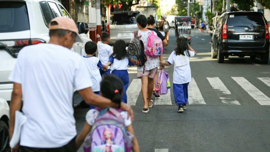 Parents accompany their children from school in Manila after dangerously high temperatures forced the Philippines to suspend in-person classes in 5,288 schools