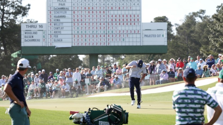 Bryson DeChambeau of the United States shields himself from the wind, blowing sand, on the 17th green at the Masters on Friday.