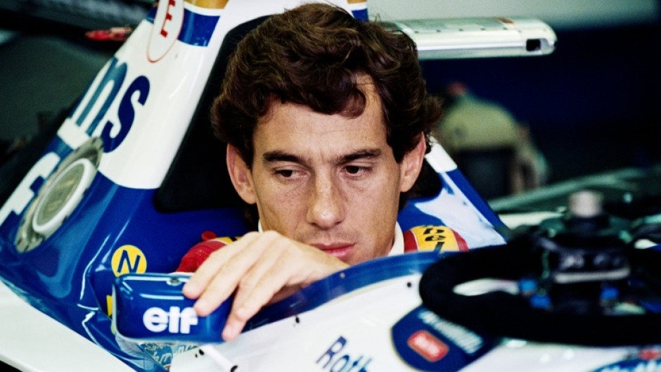 Ayrton Senna adjusts his mirror in the pits at Imola ahead of his last race