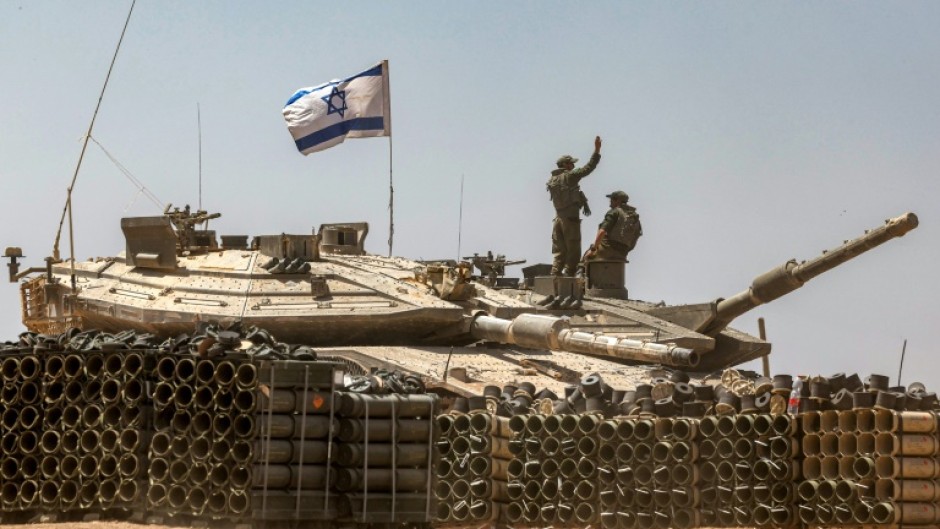 An Israeli army soldier gestures atop the turret of a main battle tank in southern Israel near the Gaza border 