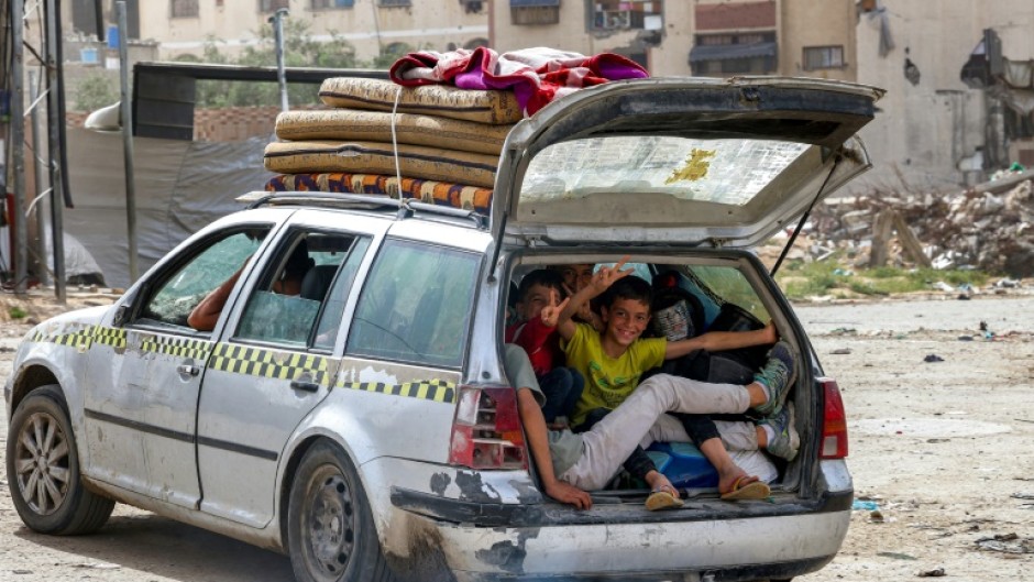 Children gesture as they sit in the back of a vehicle arriving at the Daraj quarter of Gaza City on May 11