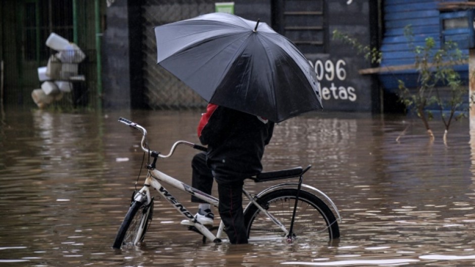 A local attempts to ride a bike in a flooded street at Santos Dumont neighbourhood in Sao Leopoldo, Rio Grande do Sul, Brazil, on May 12, 2024