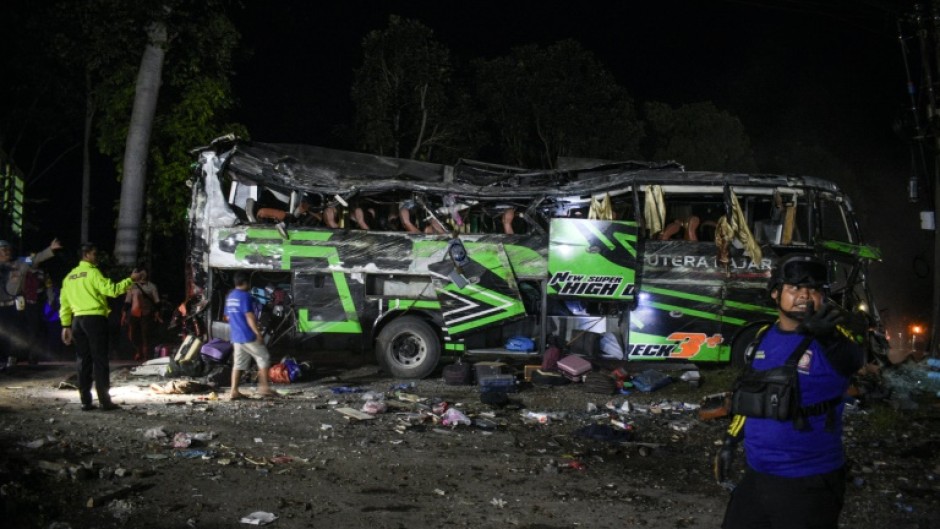 Officers check the debris and belongings of passengers after a bus crash on Java island