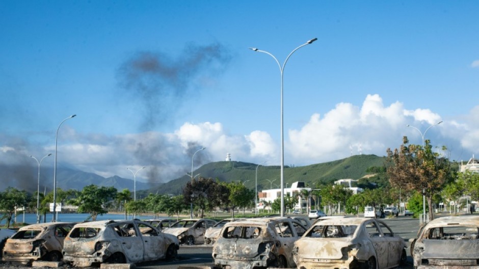 A torched residence on a street blocked by debris