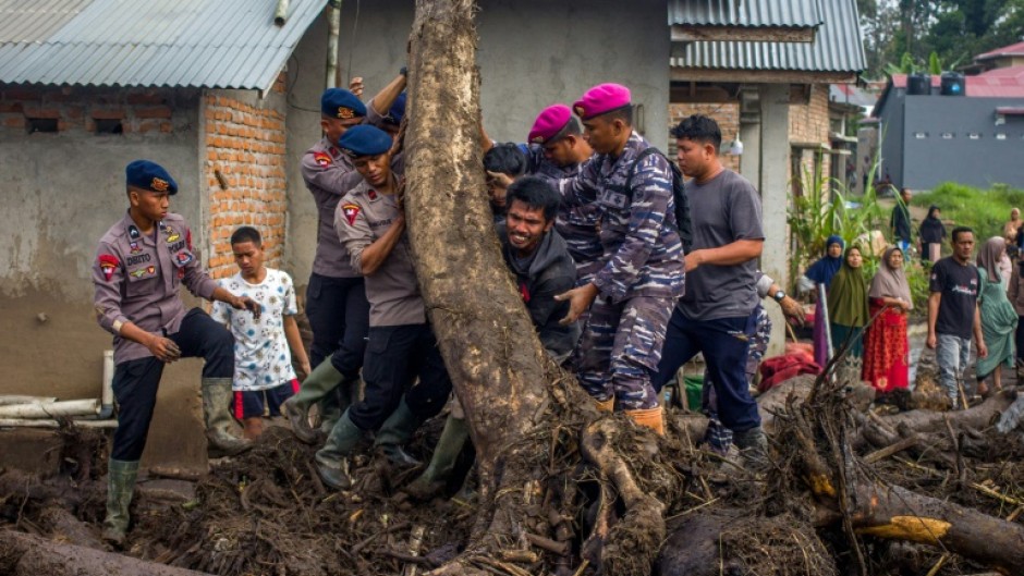 Rescue teams and people move logs that had washed into residential areas in western Indonesia