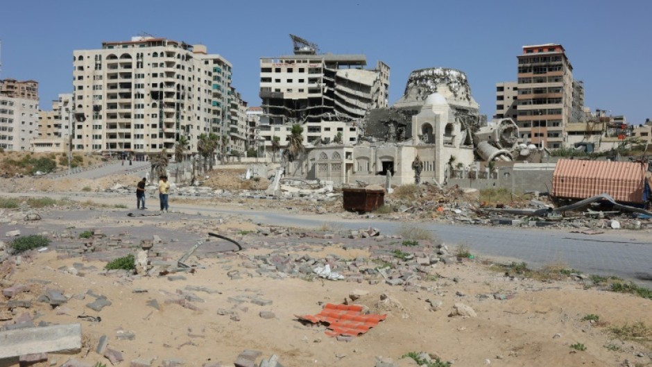 Palestinians walk past damaged and destroyed buildings in Gaza City