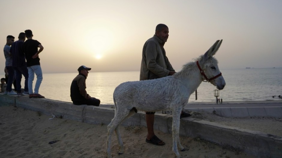 Palestinians watch as a ship transporting humanitarian aid sails in the water near the central Gaza Strip 