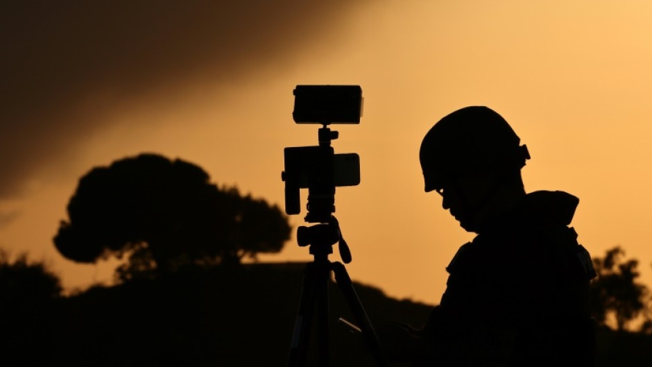 A member of the media stands behind his camera at a spot overlooking the Gaza Strip in the southern Israeli city of Sderot in a file picture taken on October 26, 2023