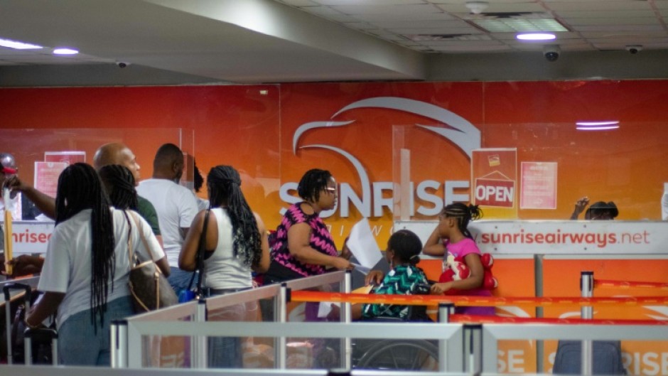 Passengers queue at the Sunrise Airways counter in Haiti's Toussaint Louverture International Airport in Port-au-Prince on May 20, 2024, the first day of commercial flights since the airport closed in March due to gang violence