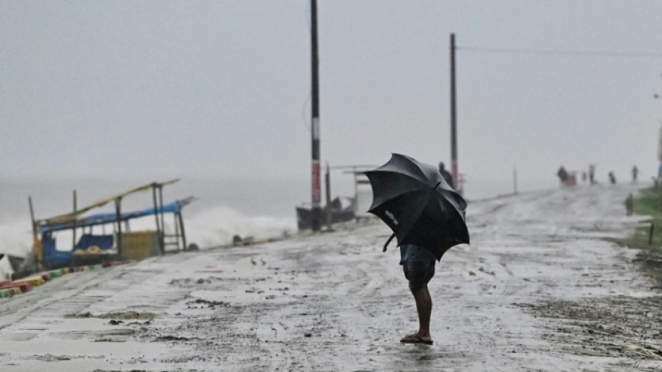 A man uses an umbrella during rainfall in Kuakata on May 26: Cyclones have killed hundreds of thousands of people in Bangladesh in recent decades, but the number of superstorms hitting its densely populated coast has increased sharply