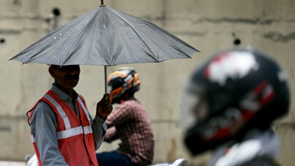 As developing countries urge increases in climate aid, a toll booth worker takes shade under an umbrella during a record heatwave in Delhi