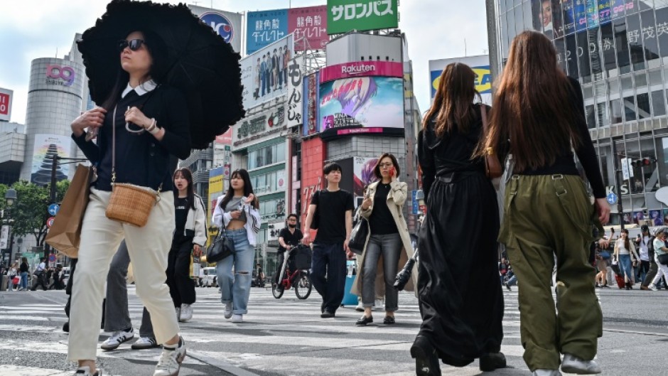 Pedestrians cross the intersection at Shibuya Crossing in Tokyo