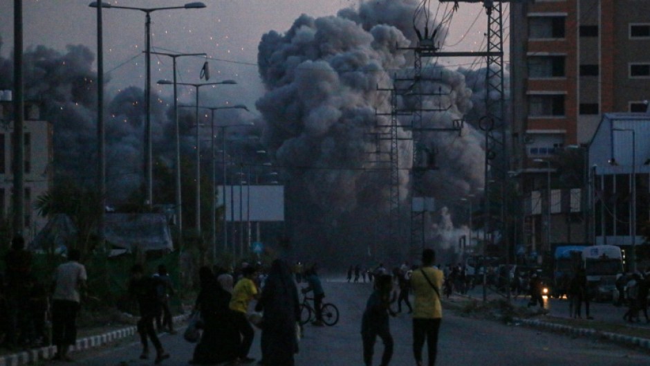 Palestinians watch smoke billowing following an Israeli air strike in Deir al-Balah