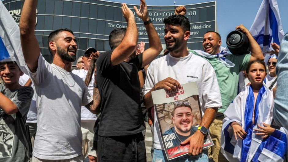 A man holds a picture of freed hostage Almog Meir Jan outside a hospital in central Israel