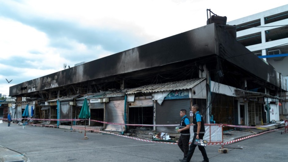 Forensics officers survey the area after a fire at a pet market next to Chatuchak market in Bangkok