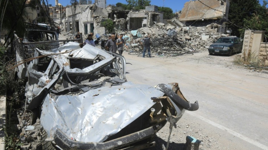 People walk past the rubble of a building that was destroyed by previous Israeli bombardment in the village of Yaroun in south Lebanon