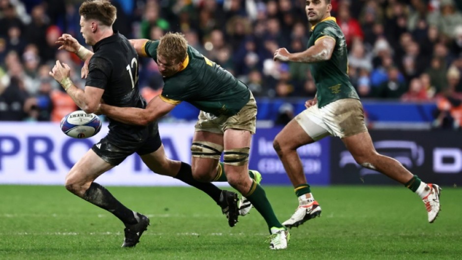 Springbok Pieter-Steph du Toit (C) tackles All Black Jordie Barrett during the 2023 Rugby World Cup final in Paris.