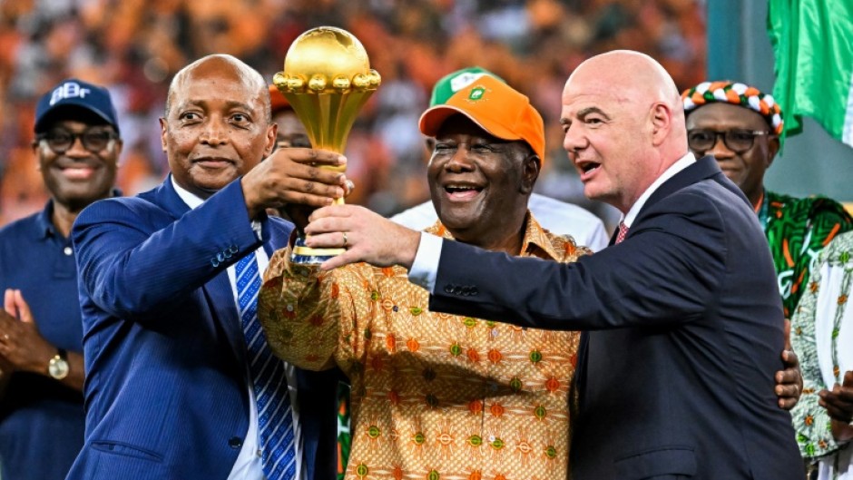 CAF president Patrice Motsepe (L), President Alassane Ouattara of the Ivory Coast and FIFA president Gianni Infantino hold the Africa Cup of Nations trophy after hosts Ivory Coast won the 2024 final.