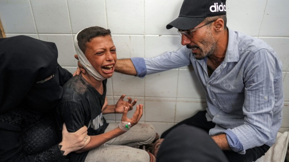 An injured boy mourning the loss of his father in a strike on central Gaza's Maghazi refugee camp, at a hospital morgue