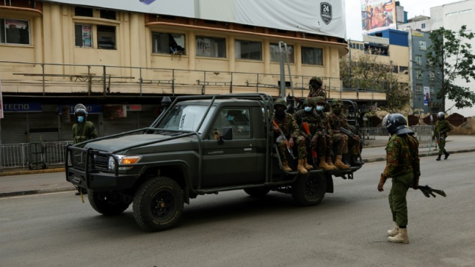 A patrol car from the Kenya Defence Forces drives past policemen during fresh demonstrations