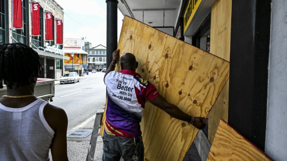 A man boards up a shop window as people prepare for the arrival of Hurricane Beryl in Bridgetown, Barbados