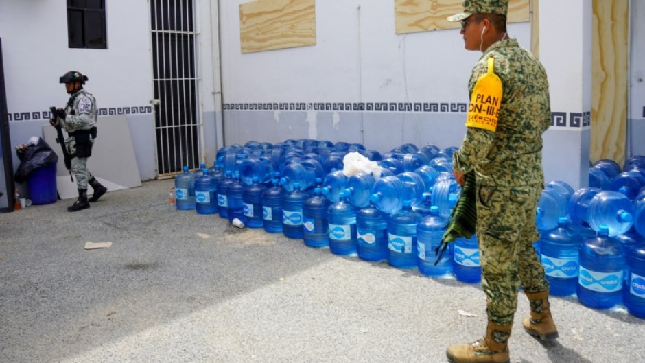 Military personnel stand close to stockpiles of water before Hurricane Beryl's arrival in Tulum