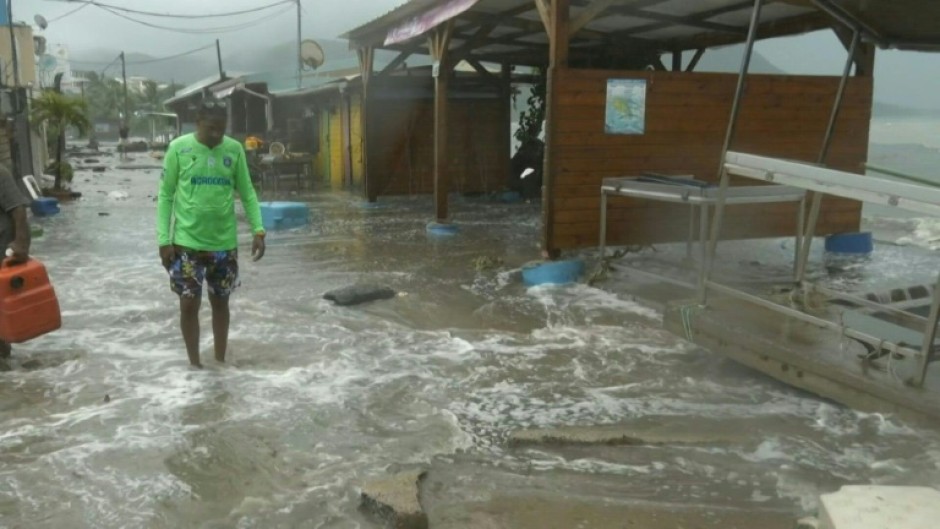 People stand outside their flooded homes after a river swelled due to heavy rains following the passage of Hurricane Beryl on the road from Cumana to Cumanacoa, Sucre State, Venezuela, on July 2, 2024