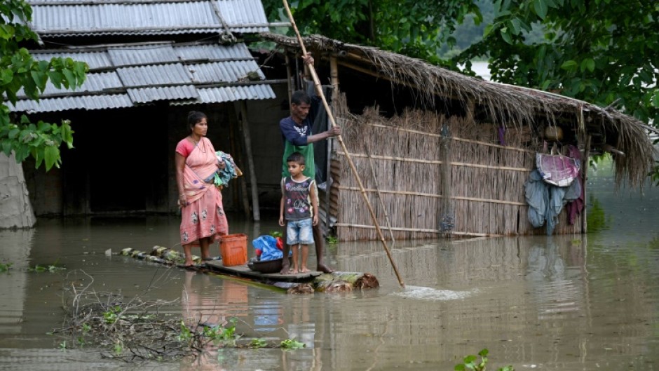 A family carries their belongings on a raft in India's flood-hit Assam state